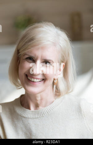 Close up di sorridere di età donna sente positivo ed energico guardando la telecamera rendendo immagine, ritratto di felice femmina senior che posano per una foto, eccitato Foto Stock