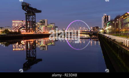 Glasgow, Scotland, Regno Unito - 4 Novembre 2018: Il moderno Clyde Arc bridge è illuminata di notte attraverso il fiume Clyde accanto all'iconico Finnieston gru in Gla Foto Stock