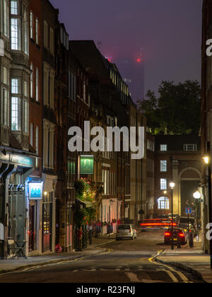 London, England, Regno Unito - 15 Ottobre 2018: case e nei pub di Londra Tempio del quartiere sono illuminate di notte con un grattacielo città semi nascosti nella nebbia Foto Stock