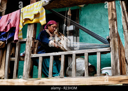 India, Himachal Pradesh, Old Manali, 08/12/2010: una donna che lavora su un telaio sul balcone della sua casa nel villaggio di Old Manali Foto Stock