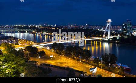 Tempo di notte vista del fiume Danubio a Bratislava, in Slovacchia, presentano la maggior parte SNP bridge. Sentiero delle luci auto visibile su strade Foto Stock