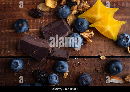 Mirtilli freschi su una tavola di legno con granola e cioccolato fondente Foto Stock
