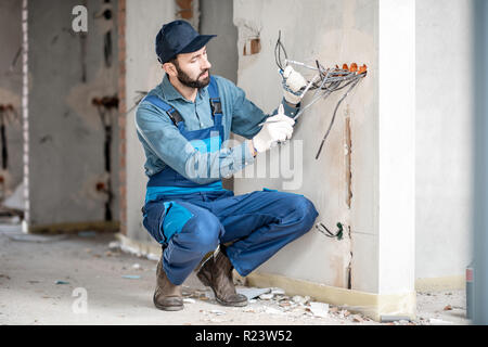 Elettricista del cablaggio del supporto per prese elettriche sul sito della costruzione di un nuovo edificio per interni Foto Stock