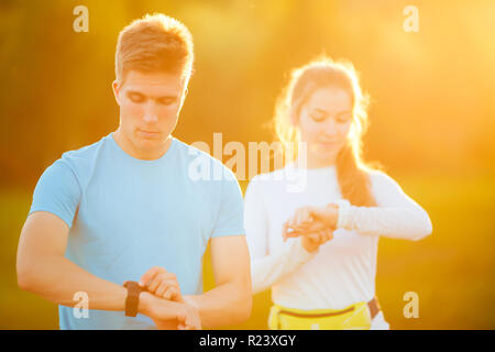 Foto di coppia giovani atleti guardando orologio nel parco sul giorno di estate Foto Stock