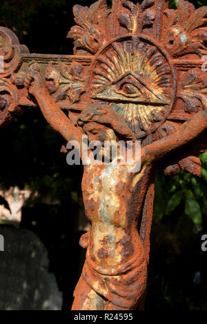 Piccolo metallo colato statua del Cristo crocifisso Gesù Cristo con un occhio della Provvidenza ( All Seeing Eye di Dio ) presso il vecchio cimitero in Serbia, dettaglio Foto Stock