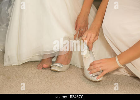 Sposa mette sul suo matrimonio scarpe in luce naturale del sole. Foto Stock