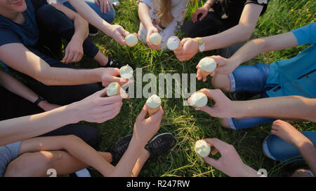 Nove amici clink bicchieri di gelato. Le mani di close-up. Foto Stock
