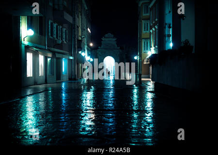 Silhouttes a piedi attraverso arco su strade in acciottolato bagnate in Zadar, Croazia Foto Stock