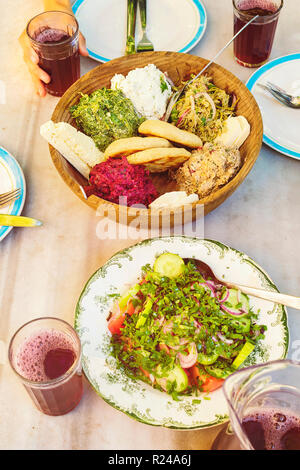 Cucina georgiana. close-up insalata di verdure, il pane di mais, formaggio nella ciotola di legno e freschi succhi di frutta naturali vista superiore Foto Stock