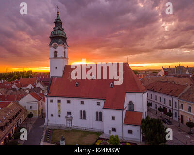 Antenna vista al tramonto della chiesa cattolica romana a Mosonmagyarovar Ungheria con vivaci viola, giallo, arancione, rosso estate cielo Foto Stock