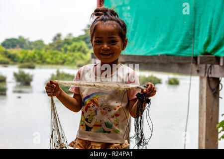 Don Det, Laos - Aprile 25, 2018: ragazza locale in possesso di una rete da pesca e fare il tifo per la telecamera in un remoto villaggio del sud Laos Foto Stock