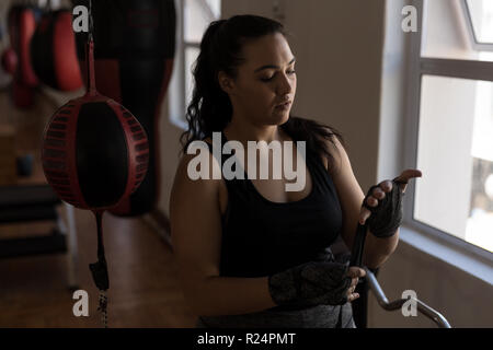 Boxer femmina indossando mano avvolgere in studio fitness Foto Stock