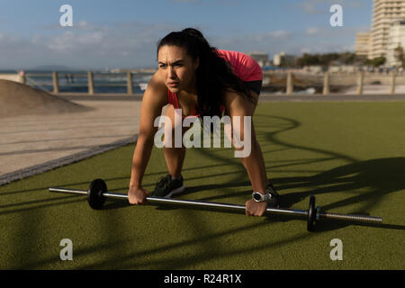 Pareggiatore femmina esercitando con barbell nel parco Foto Stock