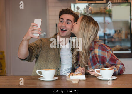 Giovane tenendo selfie in cafe Foto Stock