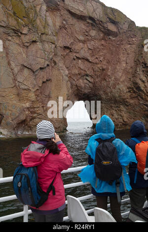 I turisti vedere e fotografare l'arco in Perce Rock off il Gaspe Penisola del Quebec, Canada. L'arco è stato creato da fenomeni di erosione da parte delle onde di th Foto Stock