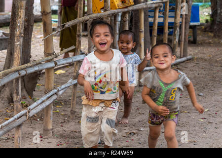Don Det, Laos - Aprile 25, 2018: i bambini poveri in esecuzione e fare il tifo per la telecamera in un remoto villaggio del sud Laos Foto Stock
