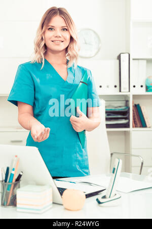 Ragazza medico sorge nei pressi di un tavolo in ufficio Foto Stock