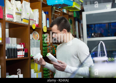 Sorridente maschio positiva di acquisto del cliente trattamento delle pulci e shampoo in petshop Foto Stock