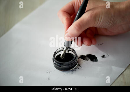 Una donna scrive a mano con inchiostro, una penna stilografica. La scrittura. Il processo creativo di creazione di un lavoro Foto Stock