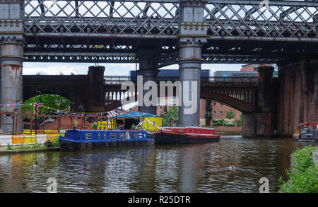 Manchester, Inghilterra, Regno Unito - 5 Giugno 2012: un contenitore treno merci attraversa Castlefield Bacino, dove la tradizionale narrowboats sono ormeggiati sul Bridgewat Foto Stock