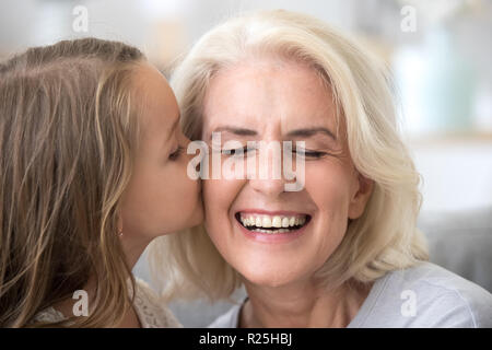 Carino piccolo nipote kissing sorridente vecchia nonna su che Foto Stock