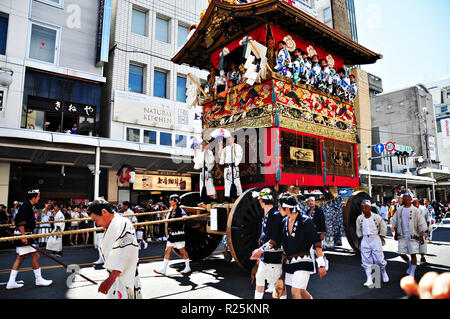 KYOTO, Giappone: un altamente decorato galleggiante lungo con i suoi disegni di uomini in tradizionali abiti giapponesi viene trascinato in un corteo durante il Gion ma Foto Stock