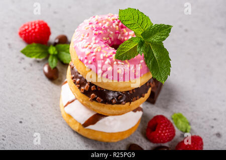 Pila di ciambelle colorate sul cemento grigio Sfondo. Parte il concetto di cibo, ad alto angolo di visione.. Foto Stock