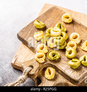 Tortellini fatti in casa con ripieno di spinaci, formaggio e ricotta su tavola di legno. Foto Stock