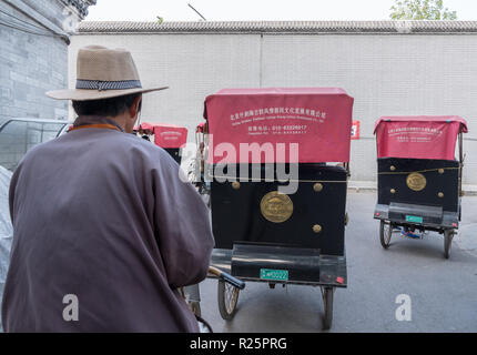 In rickshaw operatore nel distretto dell'Hutong di Pechino Foto Stock