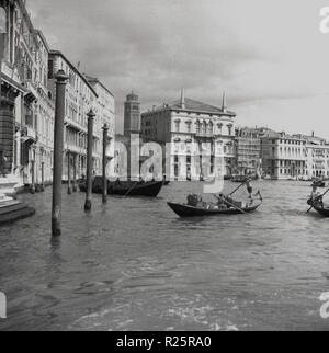 Degli anni Cinquanta, vista storica di Venezia, la celebre città italiana di piccole isole o di zone lagunari separati da canali nel paese del nord del Veneto. Emozionante e romantico, la città è piena di chiese storiche, palazzi antichi ponti e monumenti e naturalmente la famosa gondole, il tradizionale, fondo piatto veneziano barche a remi visto qui il trasporto di merci da una parte della città all'altra. Foto Stock