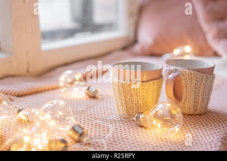 Maglia tazze di lana su un tavolo di legno. due tazze di caffè caldo. il concetto di calore. vacanze ed eventi. In autunno e in inverno, concetto di piacere. Accogliente e confortevole e morbido. Foto Stock