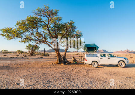 Camping sotto un'acacia, tetto tenda 4x4 car, Sossus oasi campeggio, Namibia Foto Stock