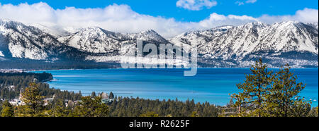 Vista panoramica verso il lago Tahoe su una soleggiata giornata chiara; montagne della Sierra coperte di neve in background; foreste sempreverdi in primo piano Foto Stock