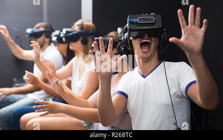 Eccitato giovane uomo europeo sperimentando con gli amici di realtà virtuale Foto Stock