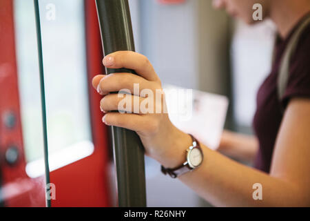 Un turista ragazza o uno studente dentro la metropolitana o il treno guarda una mappa e attende il suo arresto per andare all'esterno. Messa a fuoco selettiva per la mano. Concetto di viaggio. Foto Stock