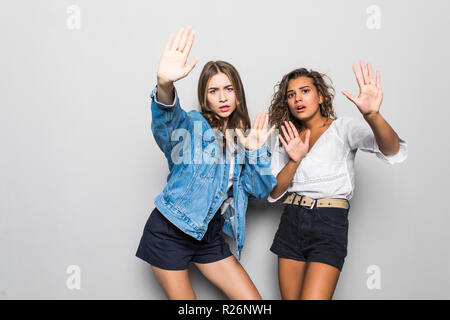 Due ragazze razza mista facendo segno di stop isolato su sfondo grigio Foto Stock