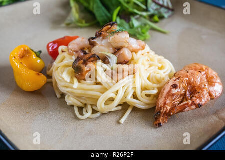 Spaghetti con le vongole Gamberi cappesante e vari frutti di mare su una piastra di ceramica di close-up. Foto Stock