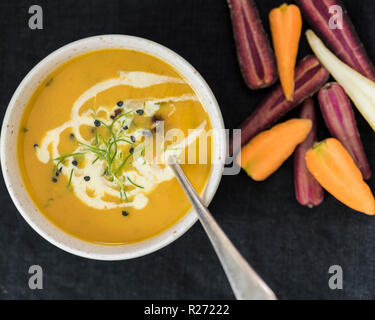 Zuppa di carote con coriandolo, crema di aglio e erba cipollina Foto Stock