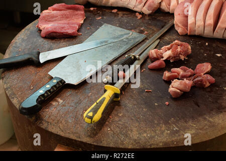 Butcher blocco tavolo in legno con carne cleaver coltello e la levigatura di acciaio. Tagliare bistecche sul tagliere. Foto Stock