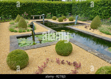 Funzione di ACQUA IN UNA COUNTRY HOUSE GARDEN. Agosto 2018. OAKHAM, RUTLAND,Inghilterra. Una decorativa acqua formale giardino con Topiaria da statue e Foto Stock