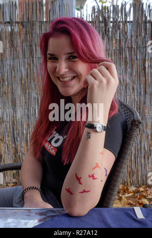 Ritratto di un sorridente giovane femmina rosso con capelli tinti e pipistrelli tatuata sul suo braccio lenti Zala county Ungheria Foto Stock