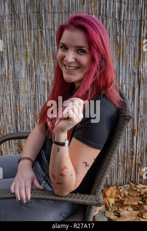 Ritratto di un sorridente giovane femmina rosso con capelli tinti e pipistrelli tatuata sul suo braccio lenti Zala county Ungheria Foto Stock