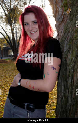 Ritratto di un sorridente giovane femmina rosso con capelli tinti e pipistrelli tatuata sul suo braccio lenti Zala county Ungheria Foto Stock