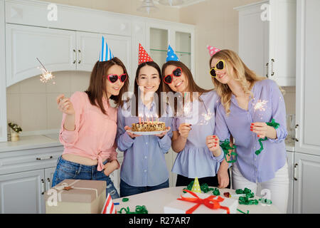 Un gruppo di amiche con una torta con candele di celebrare un birt Foto Stock