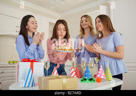 Un gruppo di amiche con una torta con candele di celebrare un birt Foto Stock