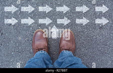 Vista superiore dell'uomo indossando scarpe scegliendo un modo contrassegnate con le frecce. Sceglie il percorso giusto concetto. Foto Stock