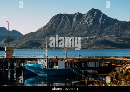 Barca sul molo e montagne vicino Slattnes, Isole Lofoten in Norvegia Foto Stock