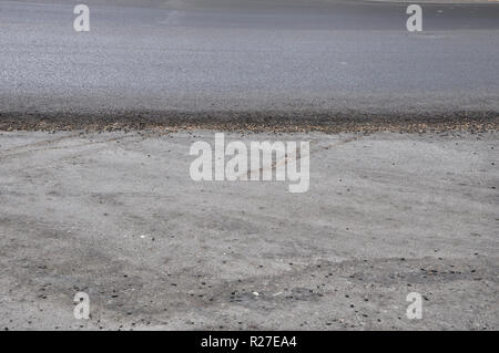 Parzialmente riparato carreggiata con un bordo orizzontale tra il nuovo asfalto disteso in concreto il lato superiore e la vecchia area di seguito. Foto Stock