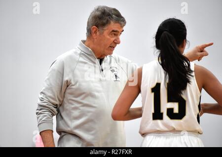 Coach fornisce istruzioni per un sostituto giocatore appena prima della sua immissione nel gioco durante un high school contest di basket. Stati Uniti d'America. Foto Stock