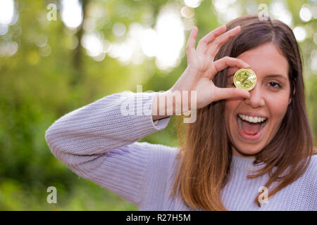 Giovani caucasici donna europea tenendo un bitcoin o cryptocurrency sorridendo felice guardando dritto con la bocca aperta e sorriso perfetto Foto Stock